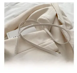 Detailed view of white woven texture shoulder bag with elegant gold metal buckle