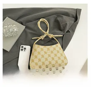 Dettaglio borsa baguette beige con motivo monogramma vintage e manico con nodo chic