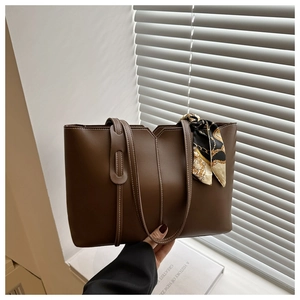 Detail of dark brown tote bag featuring contrast stitching and silk scarf wrapped handle