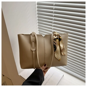 Detail of beige tote bag with V-cut top and floral silk scarf wrapped on the handle