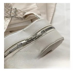 Detail of Saffiano leather heart bag featuring dual silver zippers and woven strap