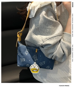 Detail of denim shoulder bag with bear print, leather strap and cupcake pendant charm