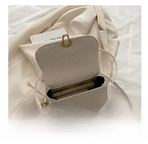 Macro view of interior storage for a white faux crocodile texture crossbody square bag