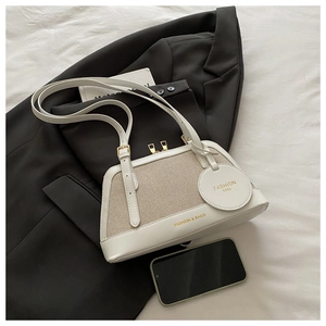 Detail of white woven underarm bag with gold zipper and stylish circular charm