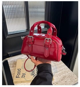 Detail of red oil wax leather handbag with glossy finish and silver metal buckles