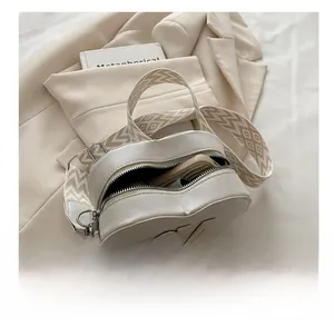 Detail of white heart-shaped leather bag showing inner capacity for a smartphone