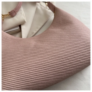 Détail du sac tricoté rose montrant la texture en V et la bandoulière en cuir souple