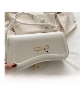 Detail showing white leather bag with gold bow clasp and wave edge flap design