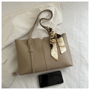 Detail of khaki tote bag with V-cut design, decorative scarf and smartphone for scale