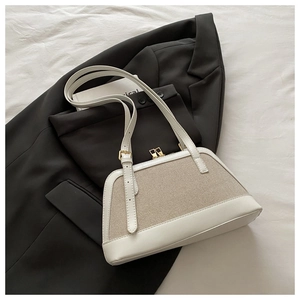 Detail of white leather and beige canvas shell bag with gold hardware on a black blazer