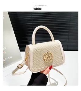 Detail of white woven texture handbag with golden M logo and adjustable leather shoulder strap