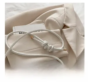 Detail of white braided shoulder strap with elegant knots and gold metal aglets