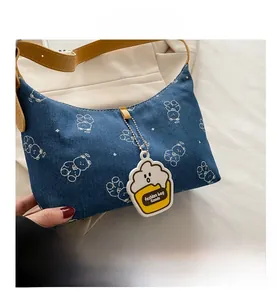 Close-up of blue denim shoulder bag with white bear patterns and yellow leather strap
