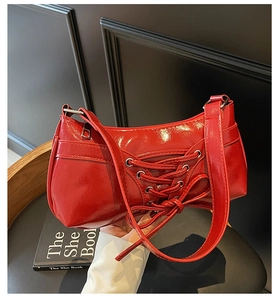 Close-up of bright red lace-up shoulder bag with bow detail and glossy PU leather texture