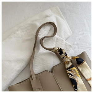 Close-up of khaki leather tote bag with geometric edges and decorative silk scarf detail