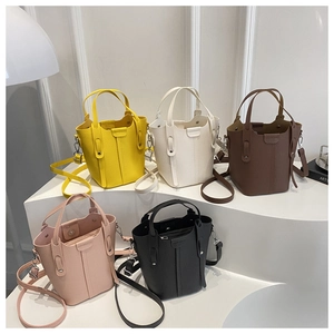 Five assorted colors of leather bucket bags with adjustable straps on a white display