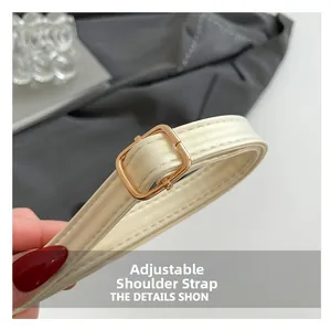Detail van de verstelbare crème lederen schouderriem met gouden metalen gesp en stiksels