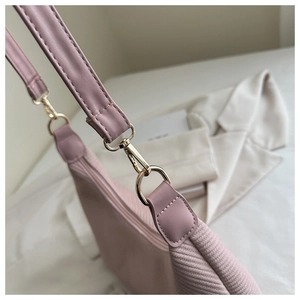 Détail du sac à bandoulière en tricot rose avec sangle en cuir et crochet en métal doré