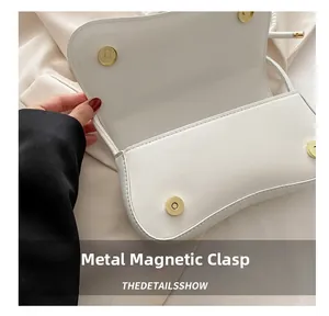 Detailed macro view of the double magnetic hardware buckles on a white flap bag