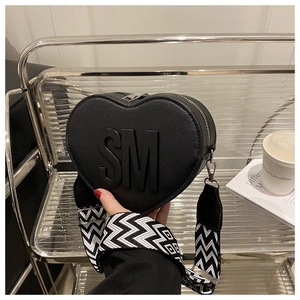 Detail of heart-shaped black bag with SM lettering and geometric woven strap
