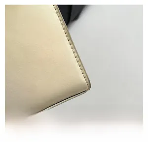 Close-up van de fijne stiksels en lederen textuur op een beige crossbody handtas