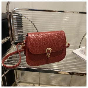 Close-up of reddish brown woven leather saddle bag featuring a gold horseshoe metal lock