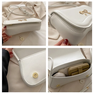 Detail view of white PU leather crossbody bag with golden bow clasp and magnetic closure