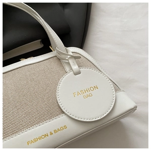 Detailed close-up of beige canvas and white leather shell bag with fashion tag