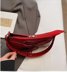 Detailed view of red glossy PU shoulder bag featuring lace-up design and silver zipper
