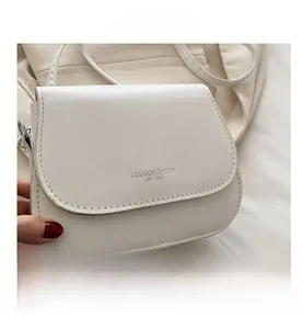 Detailed macro view of white textured leather bag with silver logo and metal buckle