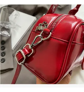 Detail of red patent leather handbag with silver lobster clasp and metal logo pendant