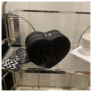 Detail of heart-shaped black bag with SM initials and wavy patterned strap