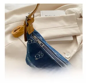 Detail of blue denim shoulder bag with white bear print and smooth silver zipper