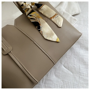 Detail of dark khaki tote bag showing matte leather texture and retro patterned silk scarf