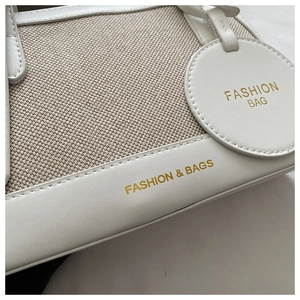 Detailed view of the creamy white leather and canvas patchwork texture with gold lettering