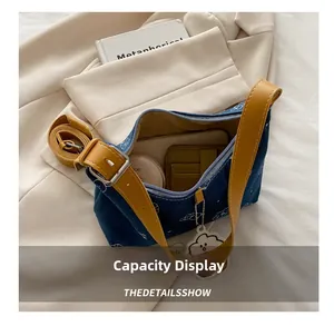 Detail view of denim underarm bag capacity showing phone and makeup accessories