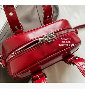 Detailed macro view of the smooth silver zipper and vintage engraved puller on red leather bag