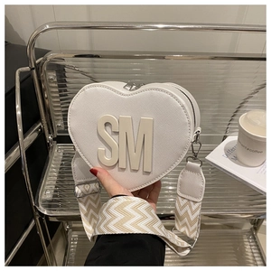 Detail of white heart-shaped PU leather bag with SM letter and zigzag strap