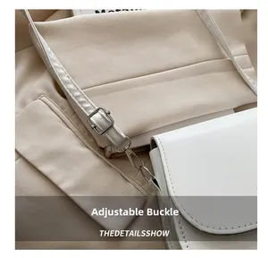 Detail of adjustable silver buckle and white leather shoulder strap on saddle bag