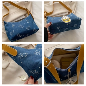 Detail view of blue denim shoulder bag with yellow strap, cartoon bear and cloud charm