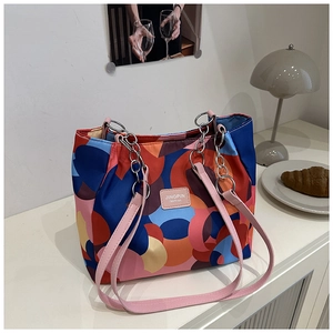 Detail of colorful geometric pattern tote bag with pink leather and metal chain strap
