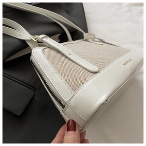 Detail of white leather and beige canvas stitching with gold zipper on shell bag