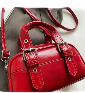 Close-up of red oil-wax leather handbag showing silver metal buckles and sturdy handles