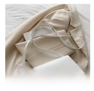 Detail view of white leather saddle bag with fashion trend text and adjustable strap