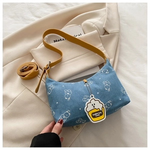 Detail of printed denim underarm bag with yellow strap and cute cupcake charm