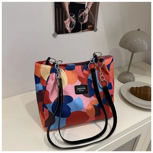 Detail of colorful geometric print tote bag with black leather handles and metal rings