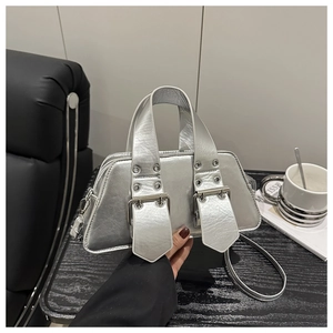 Detail der silbernen Metallic-Handtasche mit großen Schnallenösen und Trapezstruktur