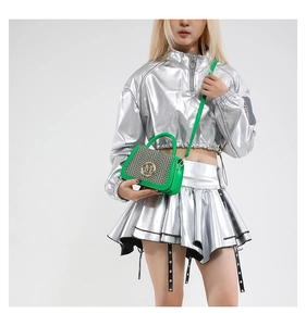 Detail of green box bag featuring a woven textured flap and golden circular metal logo