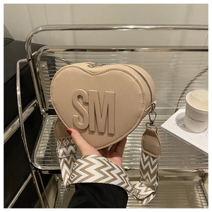 Detail of heart-shaped beige crossbody bag with embossed SM letters and wave strap