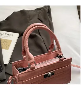 Close-up of pink faux crocodile leather handbag with silver clasp and durable handle